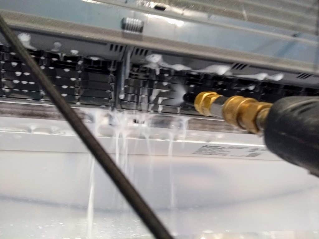 Professional pressure washing of heat pump blower wheel during deep cleaning process
