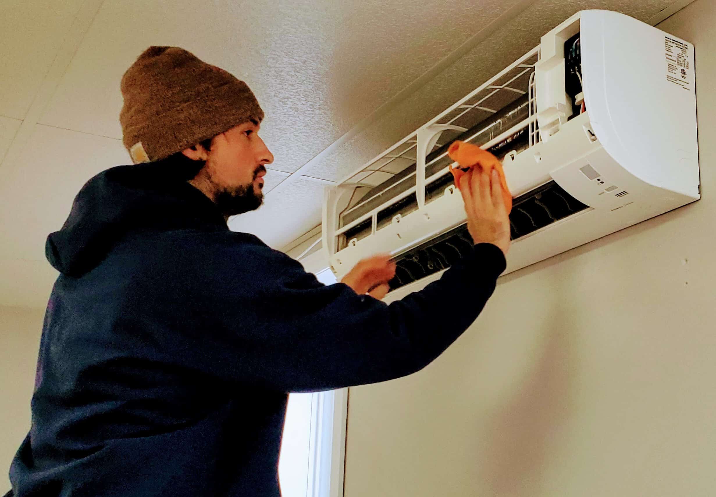 Heat pump cleaning technician servicing mini-split unit in Nova Scotia home